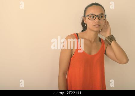 Studio-Aufnahme der jungen asiatischen Frau denken beim Zuhören und Brillen auf weißem Hintergrund Stockfoto