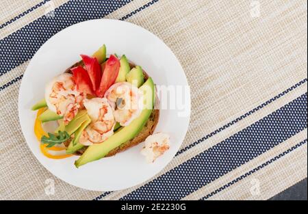 Kleines Sandwich auf einem Roggenbrötchen mit Avocado, Garnelen und Tomaten, Draufsicht, geringe Schärfentiefe Stockfoto