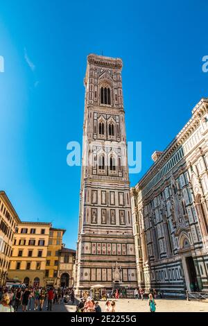 Schöne volle Aussicht auf den berühmten Giotto's Campanile von der Ostseite mit der Eingangstür. Der freistehende Glockenturm ist Teil des... Stockfoto