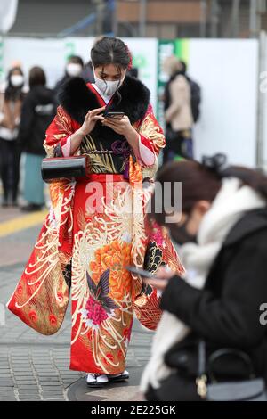 Eine Frau mit Kimono und Maske geht entlang der Straße in Shibuya Crossing während des "Coming of Age"-Tages Tokyo.Coming des Age Day feiert diejenigen, die 20 Jahre alt geworden sind. Es ist Feiertag am zweiten Montag im Januar in Japan. Angesichts der steigenden COVID19-Infektionsrate in ganz Japan war der Coming of Age Day von 2021 jedoch nicht wie gewöhnlich. Die feierliche Zeremonie war nur online in den meisten Büros der Stadt in Japan. Im beliebten Ort Shibuya Crossing waren nur wenige Mädchen in schönen Kimono. Alle Menschen tragen Maske. Stockfoto