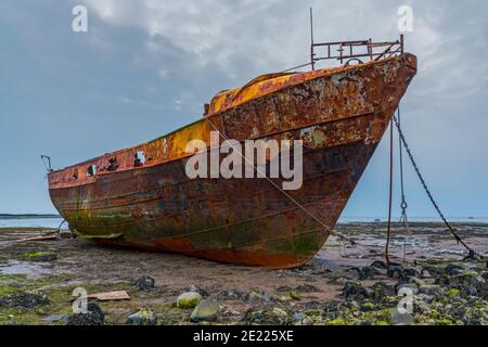 Ein rostiges Schiffswrack im Schlamm der Walney Kanal, von der Straße auf Roa Island, Cumbria, England, UK gesehen Stockfoto