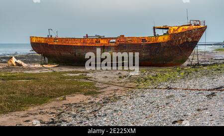 Ein rostiges Schiffswrack im Schlamm der Walney Kanal, von der Straße auf Roa Island, Cumbria, England, UK gesehen Stockfoto