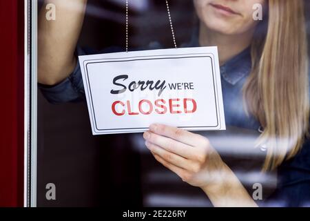 Frau hängend geschlossen Schild an kleinen lokalen Geschäft Shop Tür Angezeigt Stockfoto