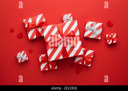 Valentinskarte mit Geschenkschachteln in Geschenkverpackung Papier mit rotem Band und Schleifen auf rotem Hintergrund mit Herzen Stockfoto