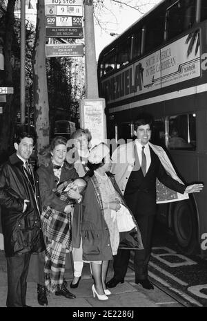 Eine Gruppe von Imitatoren der britischen Königsfamilie, die an einer Bushaltestelle anstehen, um einen roten Doppeldeckerbus zu nehmen. London. England, Großbritannien, um 1989 Stockfoto