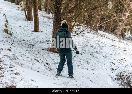 Frau, die auf dem Hang des verschneiten Waldes läuft. Extremsport im Schnee. Ein Spaziergang im Wald auf Eis Stockfoto