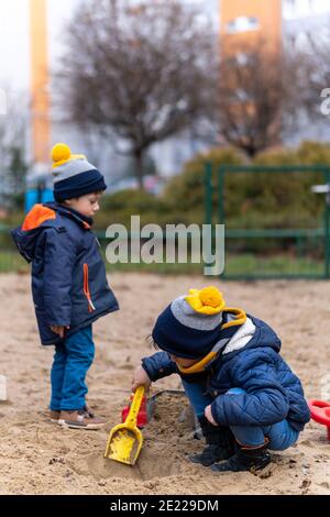 POSEN, POLEN - 25. Dezember 2020: Zwei Kinder spielen an einem kalten Wintertag auf einem Spielplatz mit Sand. Stockfoto