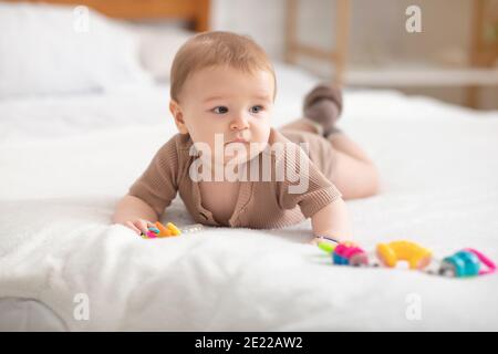 Niedliches kleines Baby, das mit Spielzeug auf dem Bett spielt Stockfoto