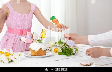 Hände von einem kleinen Mädchen und Mutter in den Prozess der Dekoration einer festlichen Kuchen. Das Konzept der Vorbereitung auf den Osterurlaub. Stockfoto