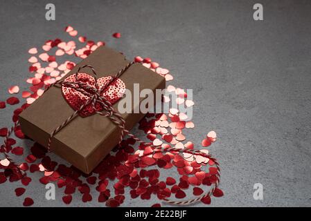 Valentinstag Geschenkbox mit Herz-Pailletten auf grauem Zement Hintergrund Stockfoto