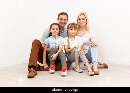 Eine glückliche Familie sitzt auf einem Holzboden. Vater, Mutter und Kind haben Spaß zusammen. Umzugshaustag, neues Hauskonzept Stockfoto