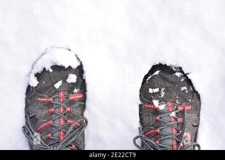 Füße in Wanderschuhen, die auf den Schnee treten. Schwarze, graue und rote Stiefel. Schneesturm genannt Filomena. La Rioja, Spanien. Stockfoto