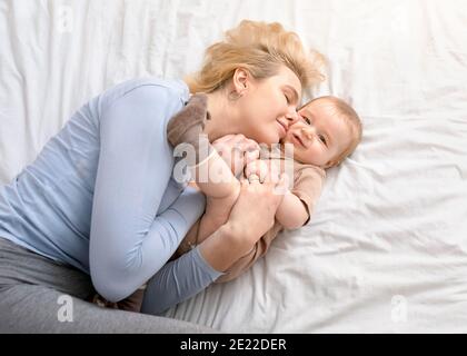 Liebevolle Mutter streichelt ihren kleinen Jungen auf dem Bett Stockfoto