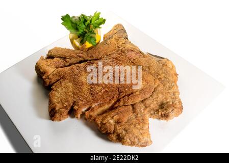 Traditionelles italienisches Kalbfleisch Milanese mit Zitrone und Petersilie, gebratenes Kotelette in Butterschmalz auf weiß isoliert Stockfoto