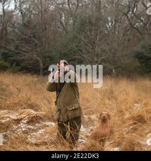 hunter und sein Schütze auf einem Holzhahn schießen Stockfoto