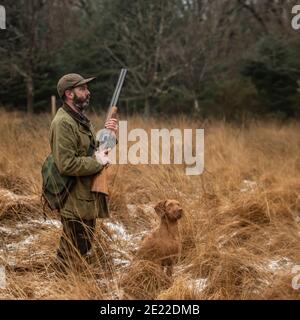 hunter und sein Schütze auf einem Holzhahn schießen Stockfoto