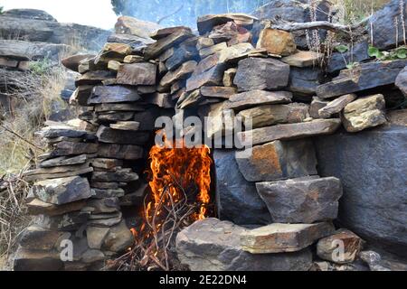 Lagerfeuer mit großen Flammen im Steinraum, um Brände zu verhindern. Feuerholz in Peroblasco, La Rioja, Spanien. Stockfoto