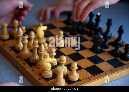 Brettspiel zu Hause. Ein Kind spielt alleine Schach. Altes Holzschachbrett. Kinderhände. Schachfiguren auf einem Schachbrett. Stockfoto