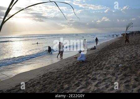 Bali, Indonesien - 12. Januar 2021: Einheimische und Touristen versammeln sich am Strand von Kuta zum Spaß, genießen Surfen und fotografieren die balinesische Kultur Stockfoto