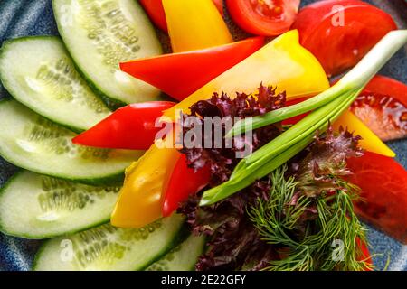 Gurken, Tomaten, grüne Zwiebeln, Paprika in Scheiben geschnitten sind auf einer Platte. Der Blick von oben. Stockfoto