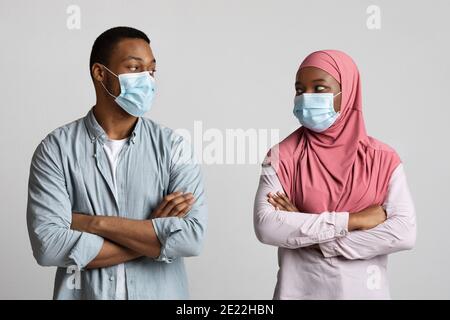Muslimische Liebhaber in Gesichtsmasken, die sich gegenseitig anblicken Stockfoto