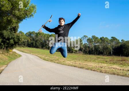 Action-Aufnahme eines jungen Skater teen männlich springen hoch Auf einer Hügelstraße Stockfoto