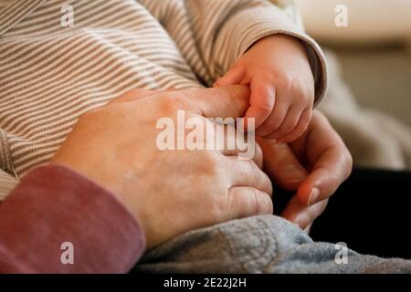 Ein 2 Monate alter Junge hält seine Mutter am Finger Mit seiner winzigen Hand Stockfoto