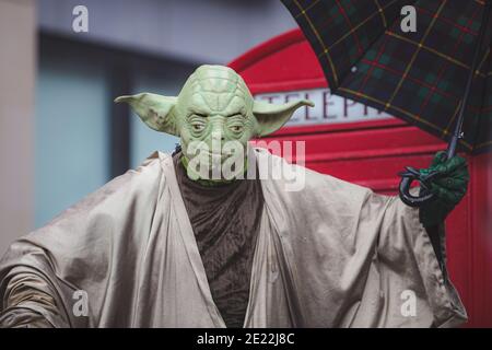 Edinburgh, Schottland - 6. August 2016: Ein Straßenkünstler in einem Yoda-Kostüm aus Star Wars posiert für die Kamera mit einem Regenschirm vor einer r Stockfoto