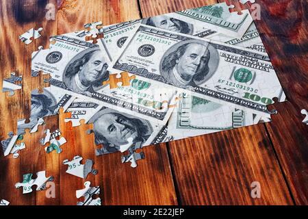 Bündel von hundert Dollar Puzzle auf rustikalen Tisch. Geschäftskonzept Finanzen und Einsparungen Stockfoto