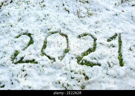 Nummer 2021 im dünnen Schnee auf dem Rasen geschrieben, so dass das Gras sichtbar wird, Neujahr Konzept oder Grußkarte, ausgewählter Fokus, enge Tiefe des Fie Stockfoto