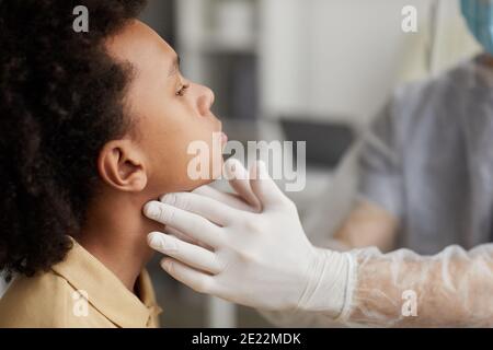 Seitenansicht Nahaufnahme eines nicht erkennbaren Arztes, der afroamerikanischen Jungen untersucht Covid während der Konsultation in der Klinik Stockfoto