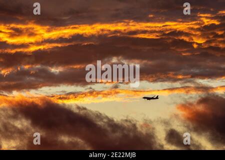 Ein kommerzielles Flugzeug steigt bei Sonnenuntergang durch Wolken ab. Stockfoto