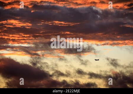 Ein kommerzielles Flugzeug steigt bei Sonnenuntergang durch Wolken ab. Stockfoto