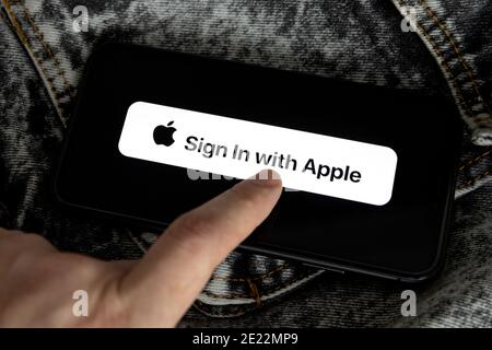 Apple ID Logo auf dem iPhone 11 Bildschirm mit schwarzem und weißem Denim Hintergrund und der Hand einer jungen Frau. Melden Sie sich mit Apple an Stockfoto