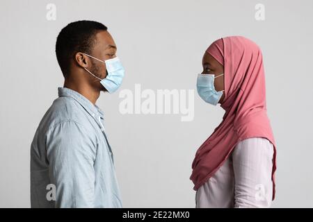 Schwarzer Mann und Frau in Schutzmasken von Angesicht zu Angesicht Stockfoto