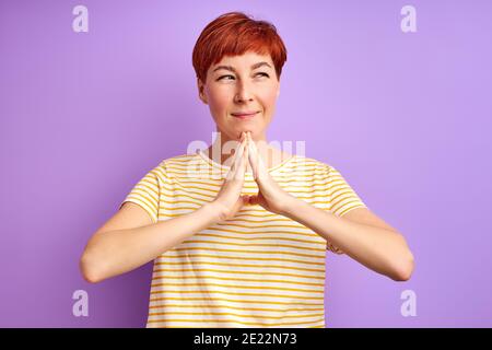 Weiblich ist begreifen etwas, das auf Seite, junge Frau in Casual tragen stehen denken, die Hände zusammen Stockfoto