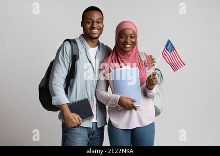 Fröhliche schwarze muslimische Studenten Paar mit amerikanischer Flagge Stockfoto