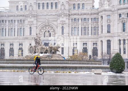 Spanien, Madrid; 8. Januar 2021: Schneesturm 'Filomena' in der Madrider Innenstadt am Plaza De Cibeles und ein Lieferjunge überquert den Platz Stockfoto