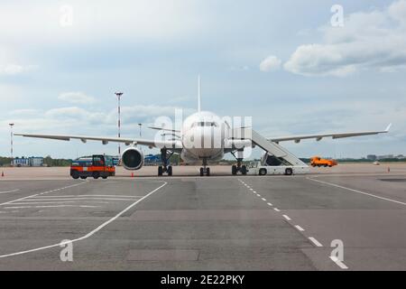 Passagierflugzeug mit Einstiegsstufen, das vor dem Flug auf das Einsteigen von Passagieren und Gepäck wartet Stockfoto