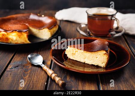 Ein Stück köstlichen baskischen gebrannten Käsekuchen mit Tasse Tee Stockfoto