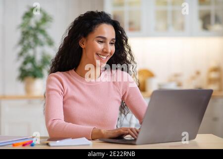 Glücklich schöne junge Freiberuflerin arbeiten auf Laptop in der Küche Stockfoto