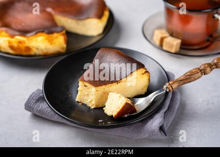 Cremiger baskischer gebrannter Käsekuchen mit einer Tasse Tee Stockfoto
