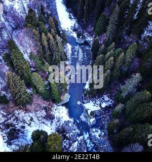 Blick von oben auf einen Bergfluss in der Taiga. Der Bergfluss im Wald im Winter. Stockfoto