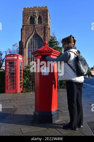 Frau postet einen Brief in einem viktorianischen sechseckigen Briefkasten in Shrewsbury, Großbritannien. Eines von nur 50 hergestellt wurden sie von I.W. entworfen Penfold und hergestellt von C Stockfoto