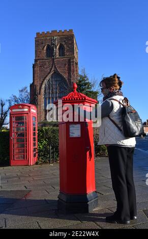 Frau postet einen Brief in einem viktorianischen sechseckigen Briefkasten in Shrewsbury, Großbritannien. Eines von nur 50 hergestellt wurden sie von I.W. entworfen Penfold und hergestellt von C Stockfoto