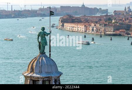 Schutzengel - EINE Bronzestatue, die auf der Spitze der Kuppel der Basilika San Giorgio Maggiore steht und über dem geschäftigen Giudecca-Kanal wacht. Venedig, Italien. Stockfoto