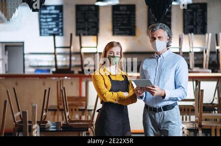 Frustrierter Besitzer mit Kellnerin in geschlossenem Cafe, kleine Unternehmen geschlossen wegen Coronavirus. Stockfoto