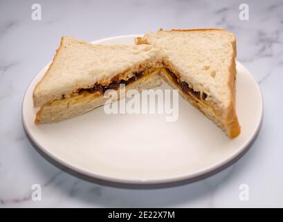 Norwich, Norfolk, Großbritannien – November 22 2020. Illustratives redaktionelles Foto eines Käse- und Gurkensandwiches auf weißem Brot auf weißem Teller Stockfoto