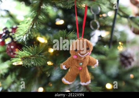 Ein gestrickter glücklicher/ lächelnder Lebkuchenmann/ Frau/ Person Kugel/ Weihnachten Baumschmuck hängt an einem Weihnachtsbaum Stockfoto