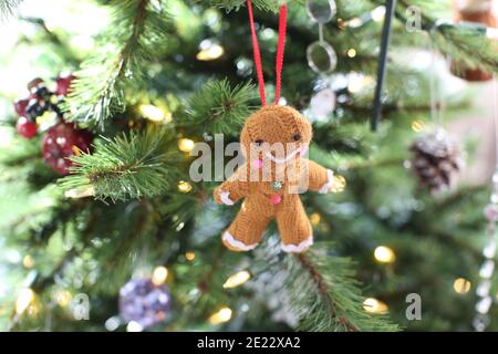 Ein gestrickter glücklicher/ lächelnder Lebkuchenmann/ Frau/ Person Kugel/ Weihnachten Baumschmuck hängt an einem Weihnachtsbaum Stockfoto